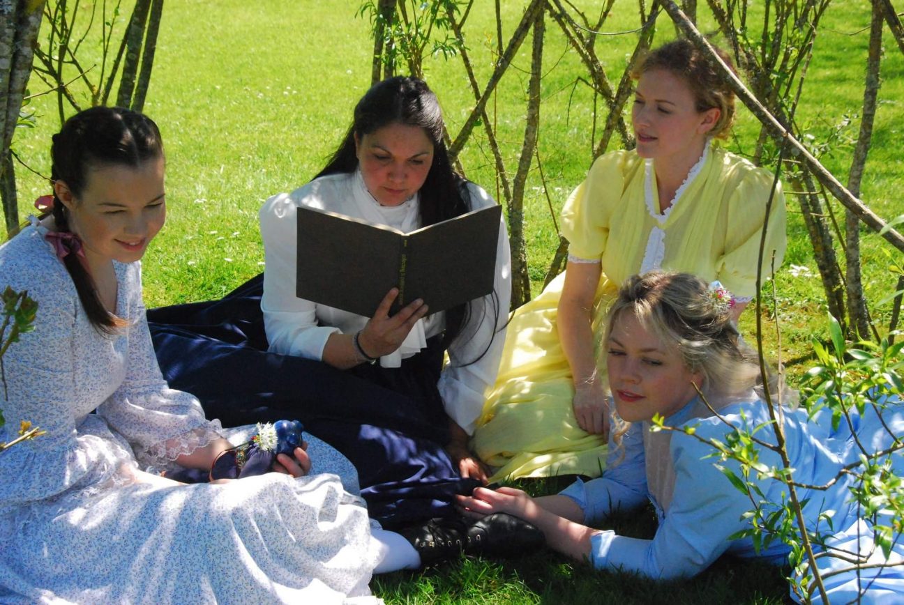 The March sisters listen to Jo read on the grass